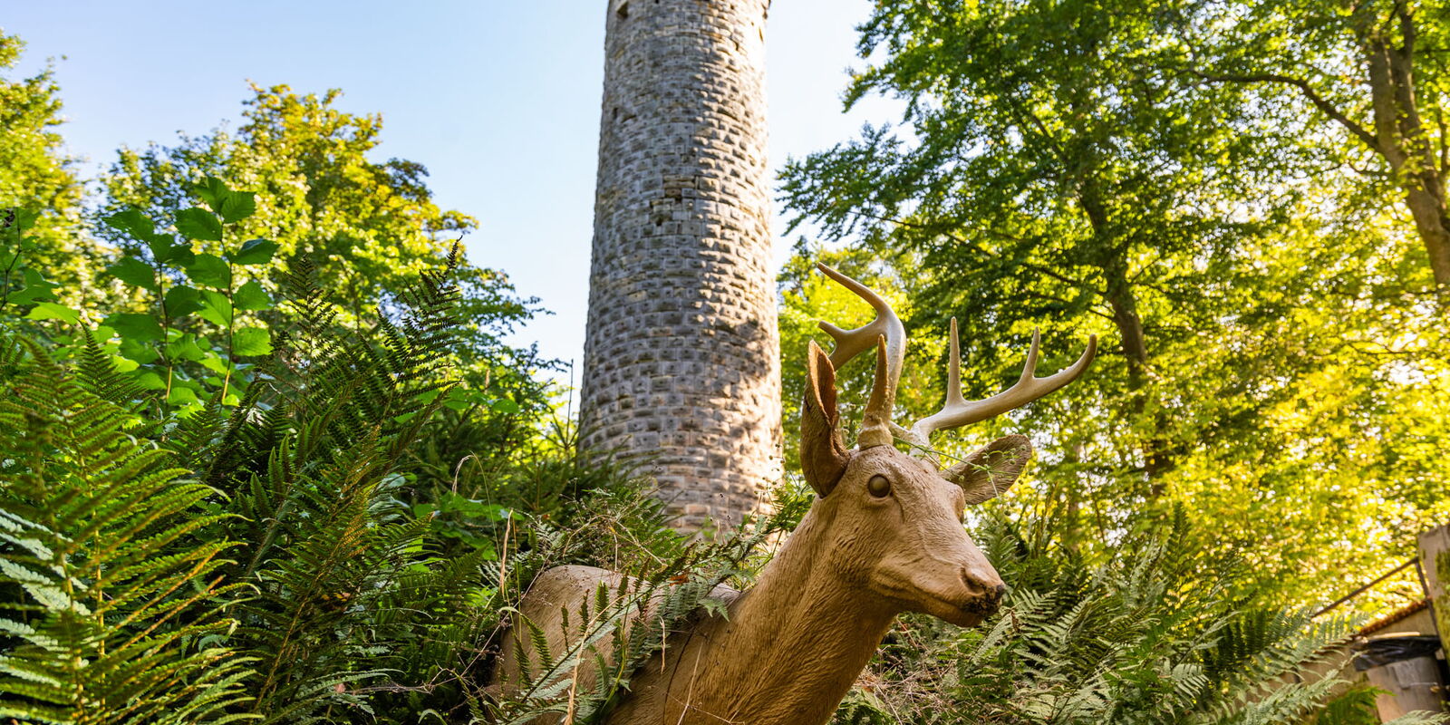 Wallenburger Turm mit einer Reh-Holzskulptur im Vordergrund